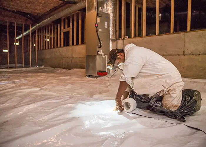 Crawl Pros professional installing a vapor barrier in a crawl space
