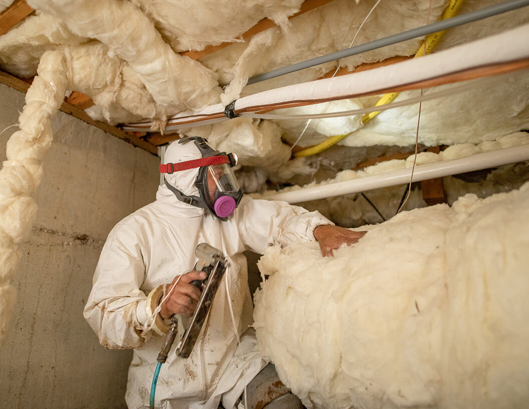 Crawl Pros worker installing insulation in a crawlspace