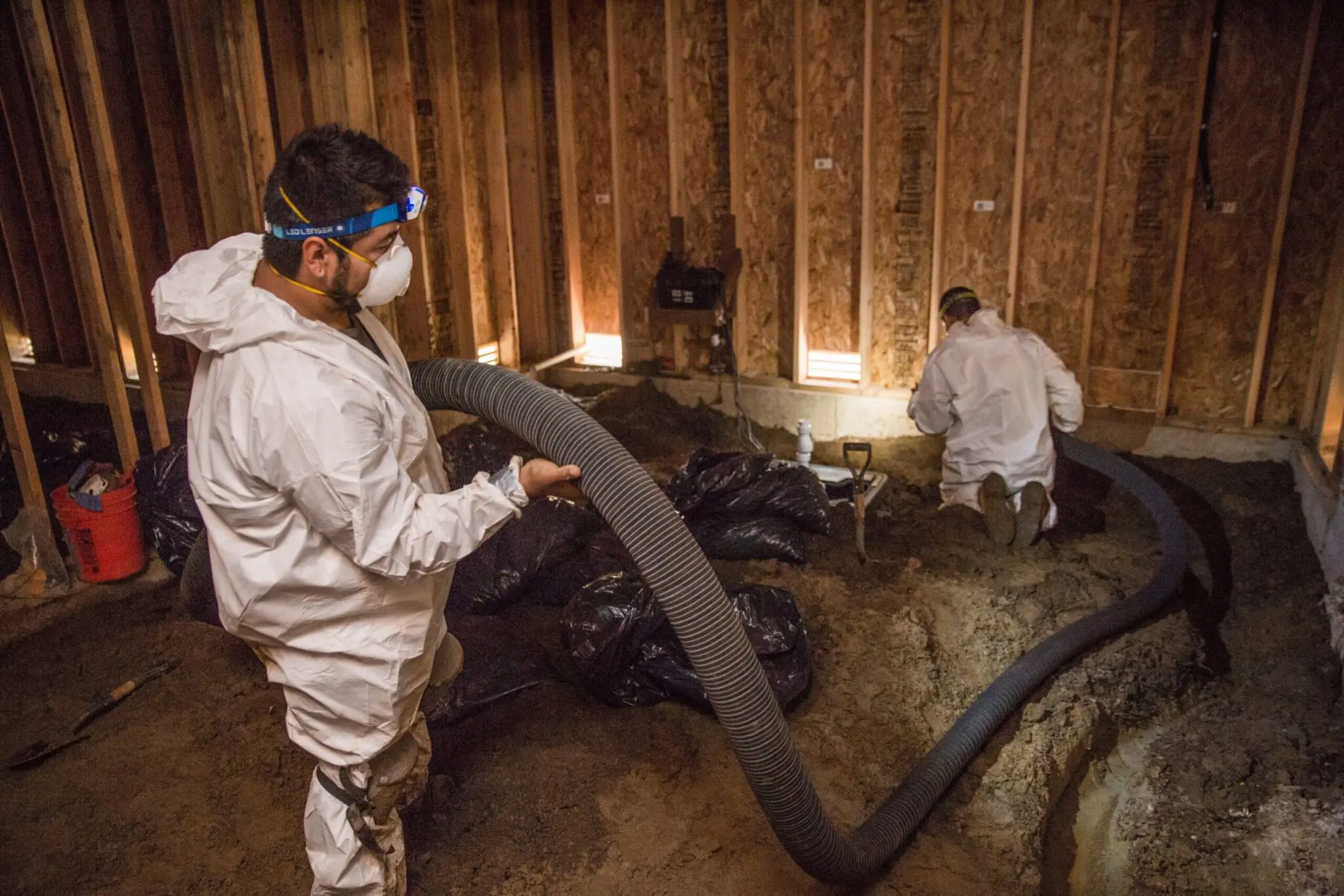Crawl Pros professionals performing a radon mitigation in a crawl space