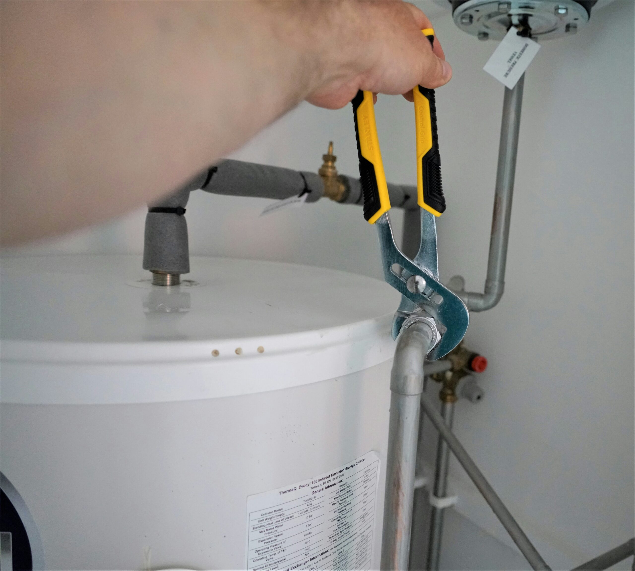Plumber performing crawl space residential plumbing services by tightening a water pipe using a wrench